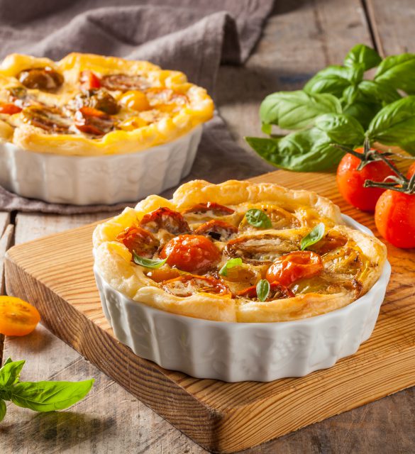 Quiche with cherry tomatoes on a rustic wooden table.