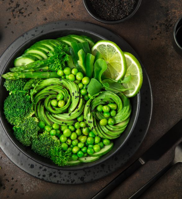 avocado, cucumber, broccoli, asparagus and sweet peas salad, fresh green vegan detox lunch bowl. Dark background. top view