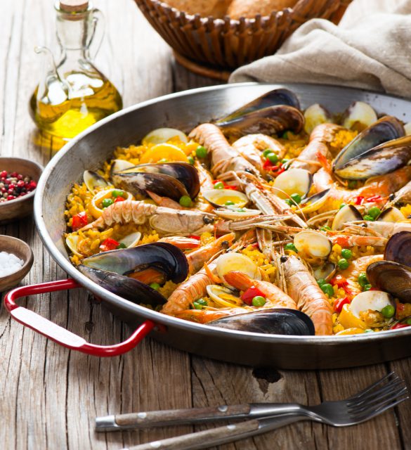 Traditional seafood paella in the fry pan on a wooden old table
